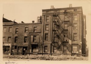A sepia image of a multistory hotel with a fire escape prominently shown on the side.